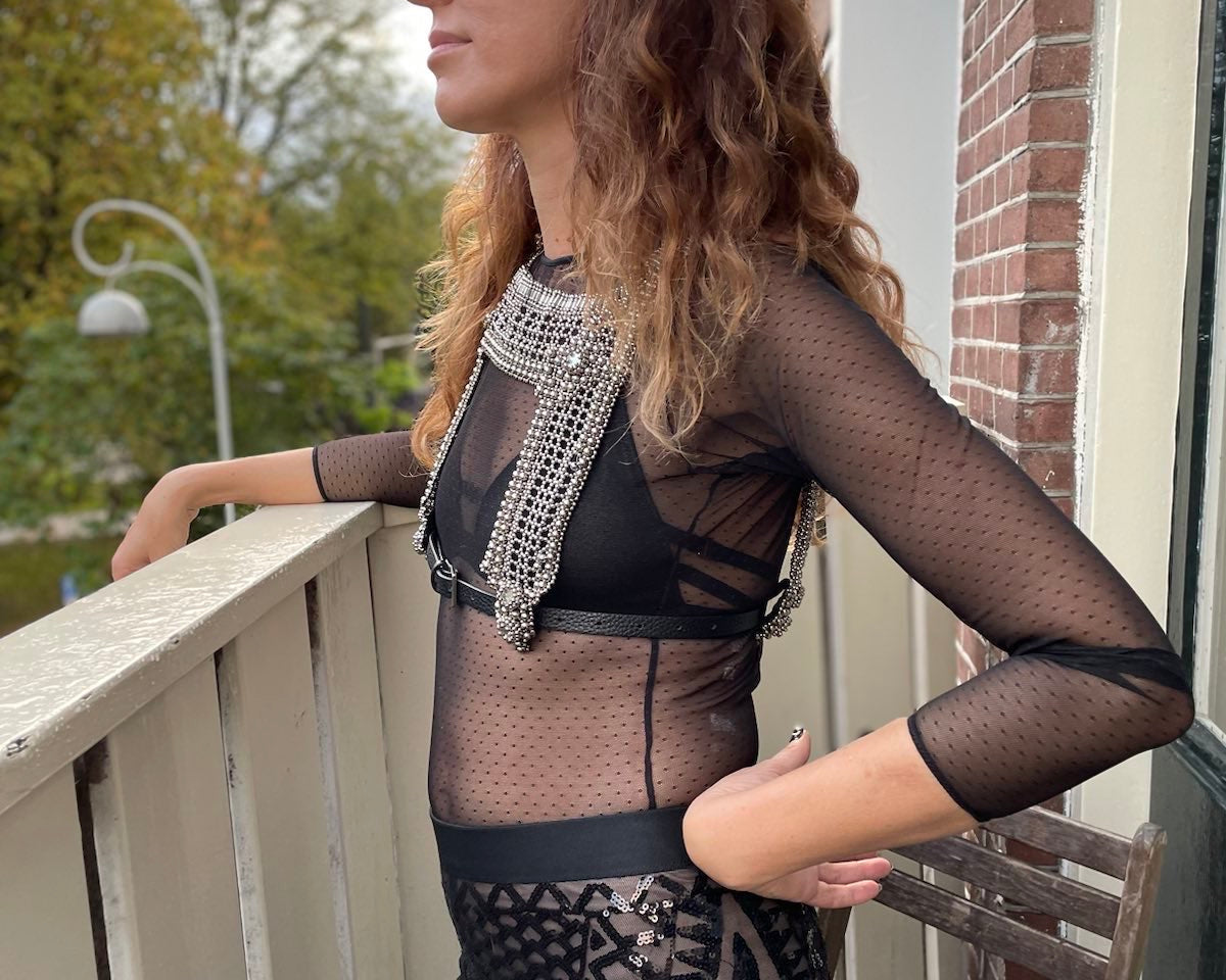Saida Mouradova standing on a balcony wearing the Artemisia Mesh Top in Silver.