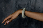 Handcrafted modular bracelet cuff from syntethic japanese pearl on wrist of woman in dark blue background
