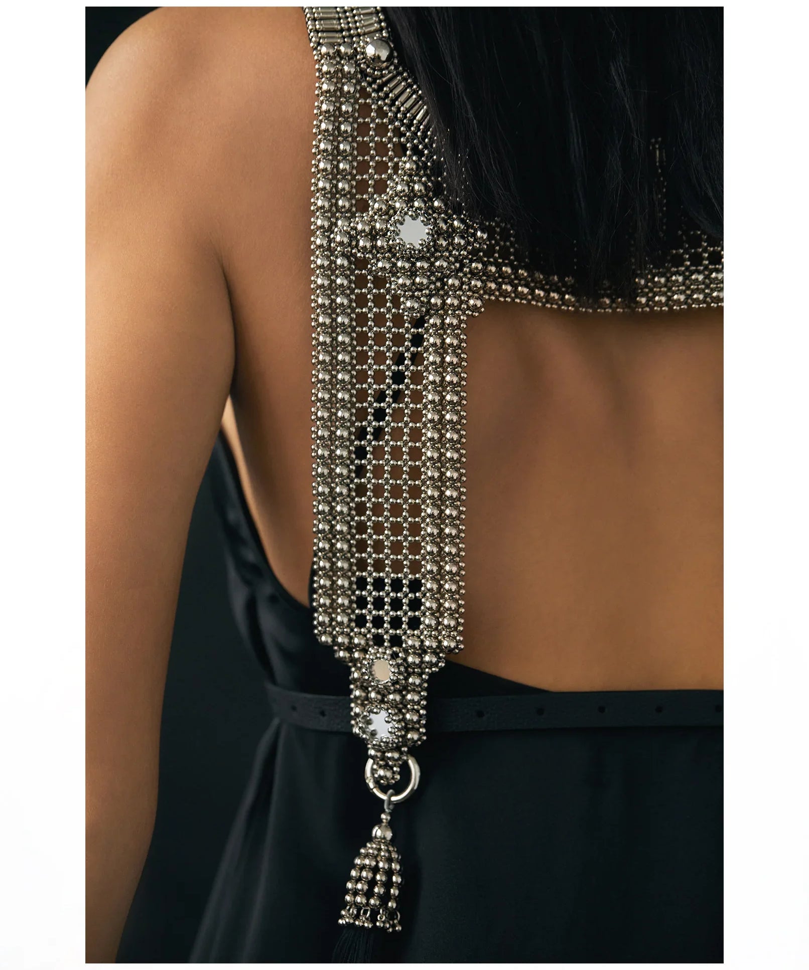 Woman wearing a black dress with silver beaded top and matching choker necklaces on white background close up 