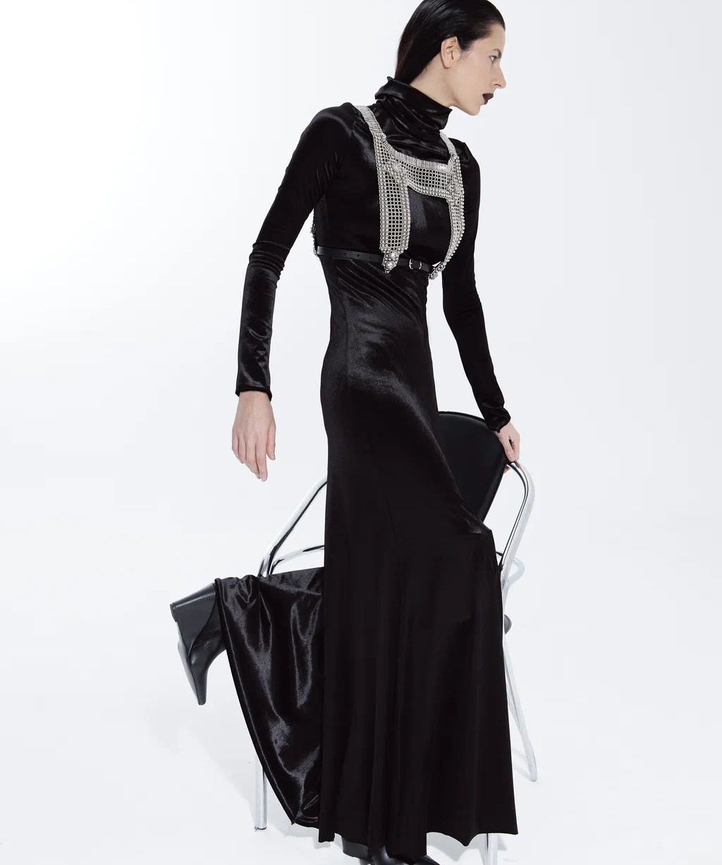 Woman wearing a black evening gown with a silver embellished top on a white background