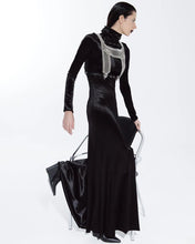 Woman wearing a black evening gown with a silver embellished top on a white background