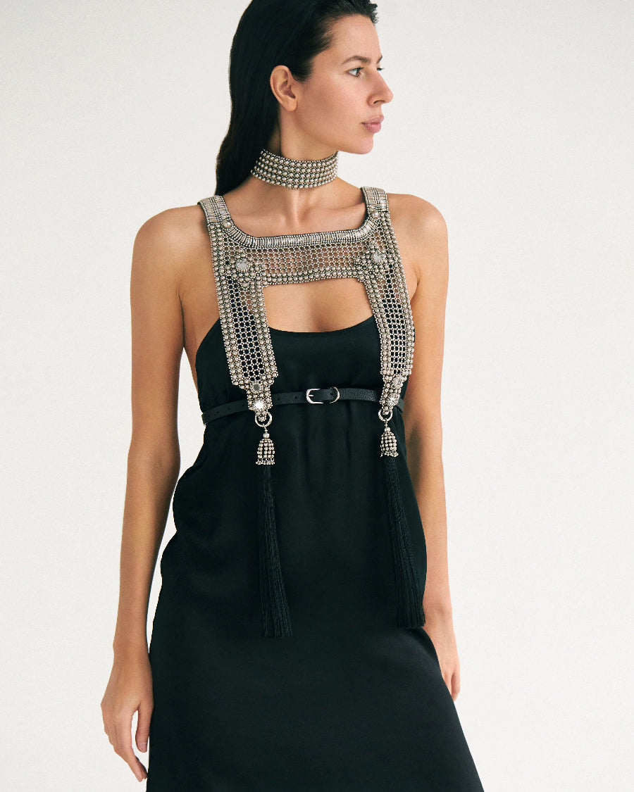 Woman wearing a black dress with silver beaded top and matching choker necklaces on white background