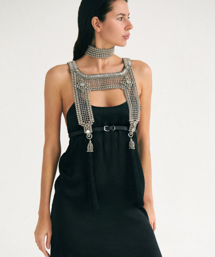 Woman wearing a black dress with silver beaded top and matching choker necklaces on white background