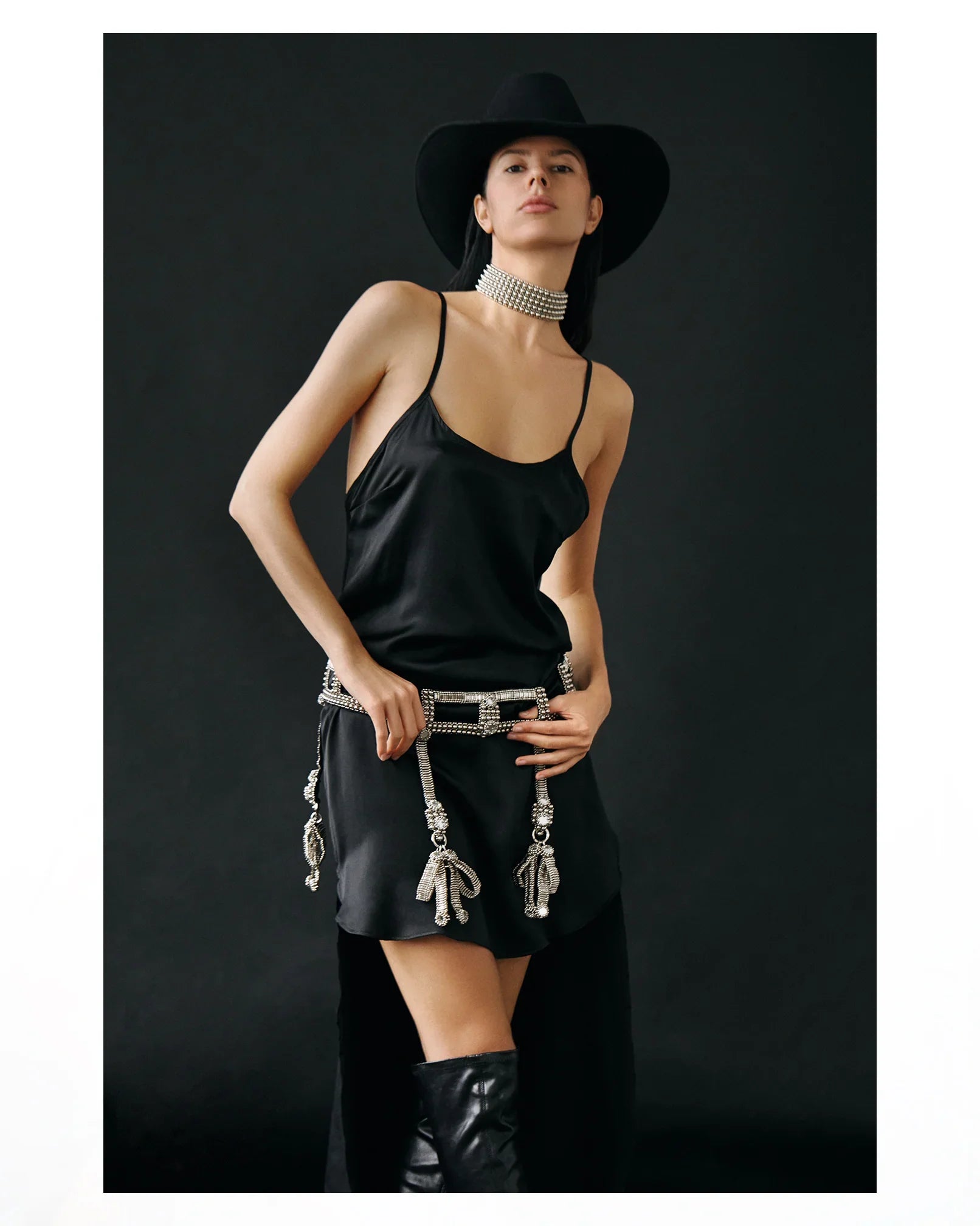 woman standing wearing black hat and black teuta dress celestial choker and teuta belt in silver by Object & Dawn on a black background