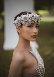 Woman wearing a decorative headpiece with a blurred outdoor background