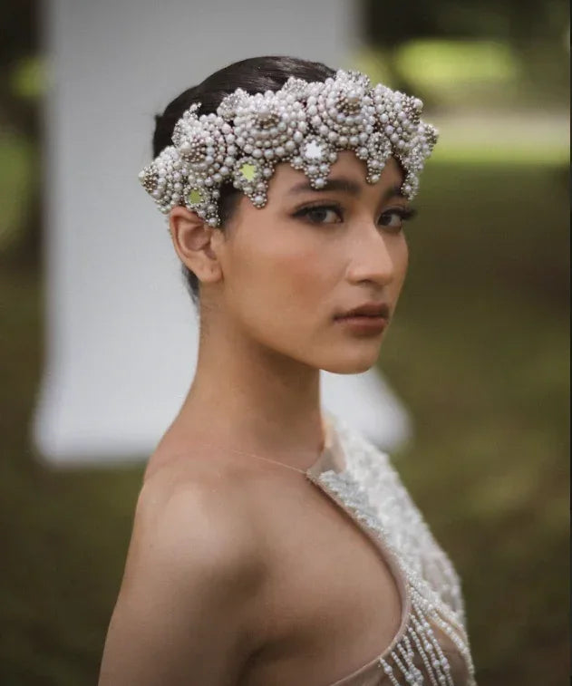 Woman wearing a decorative headpiece with a blurred outdoor background