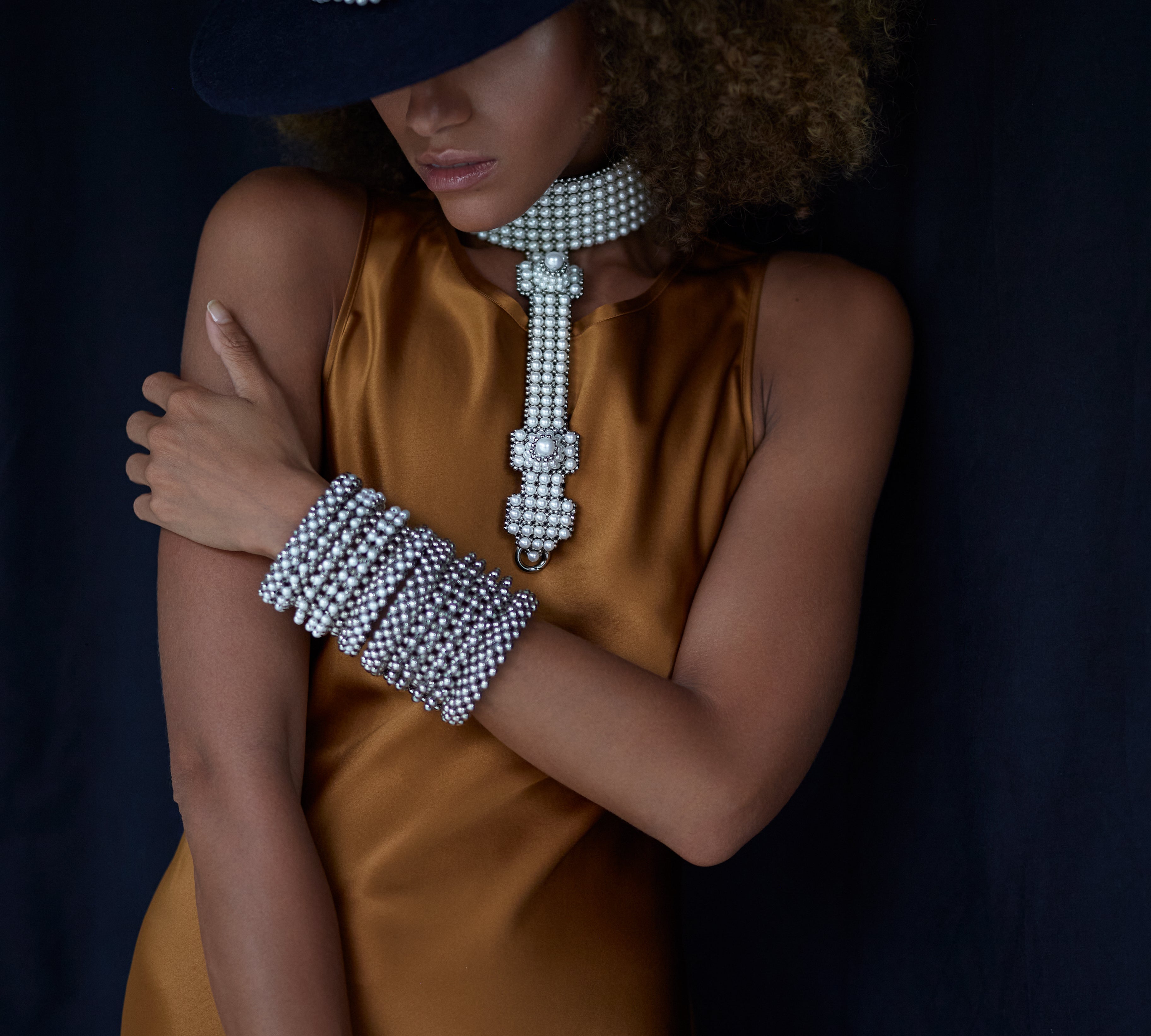 woman in brown dress with black hat wear beaded modular choker in pearl from Object and Dawn front view