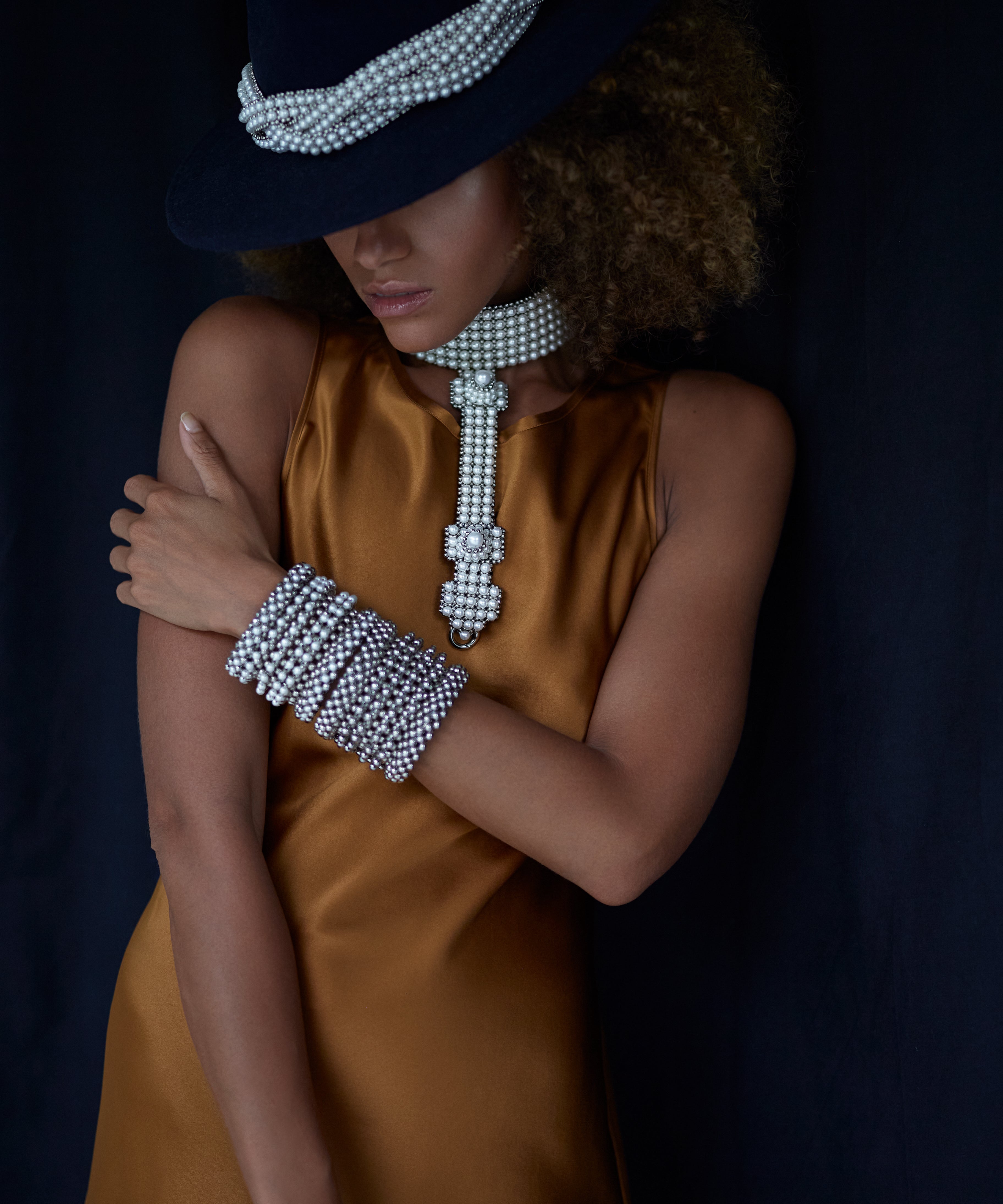 woman in brown dress with black hat wear beaded modular choker in pearl from Object and Dawn front view