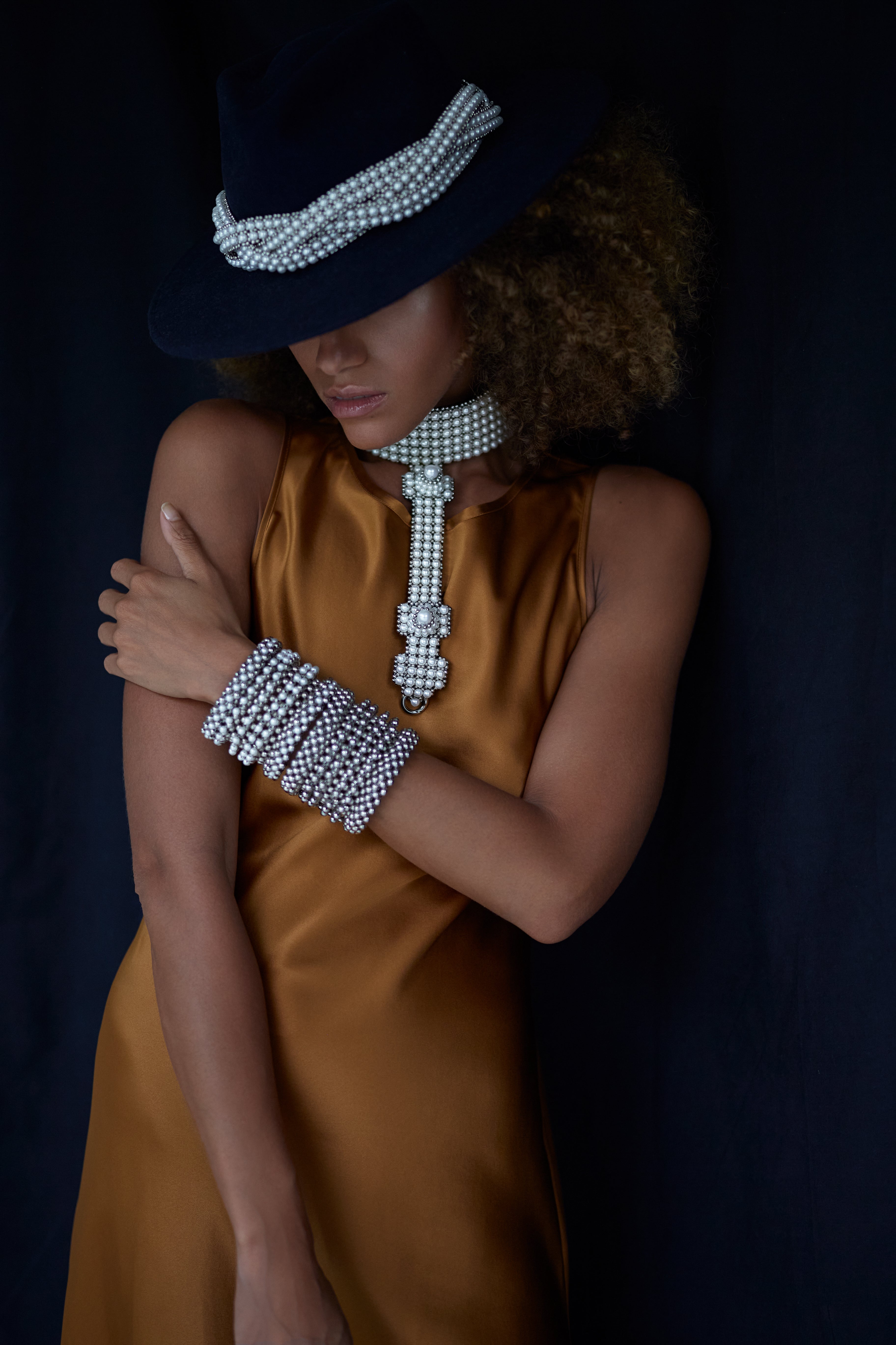 woman in brown dress with black hat wear beaded modular choker in pearl from Object and Dawn front view
