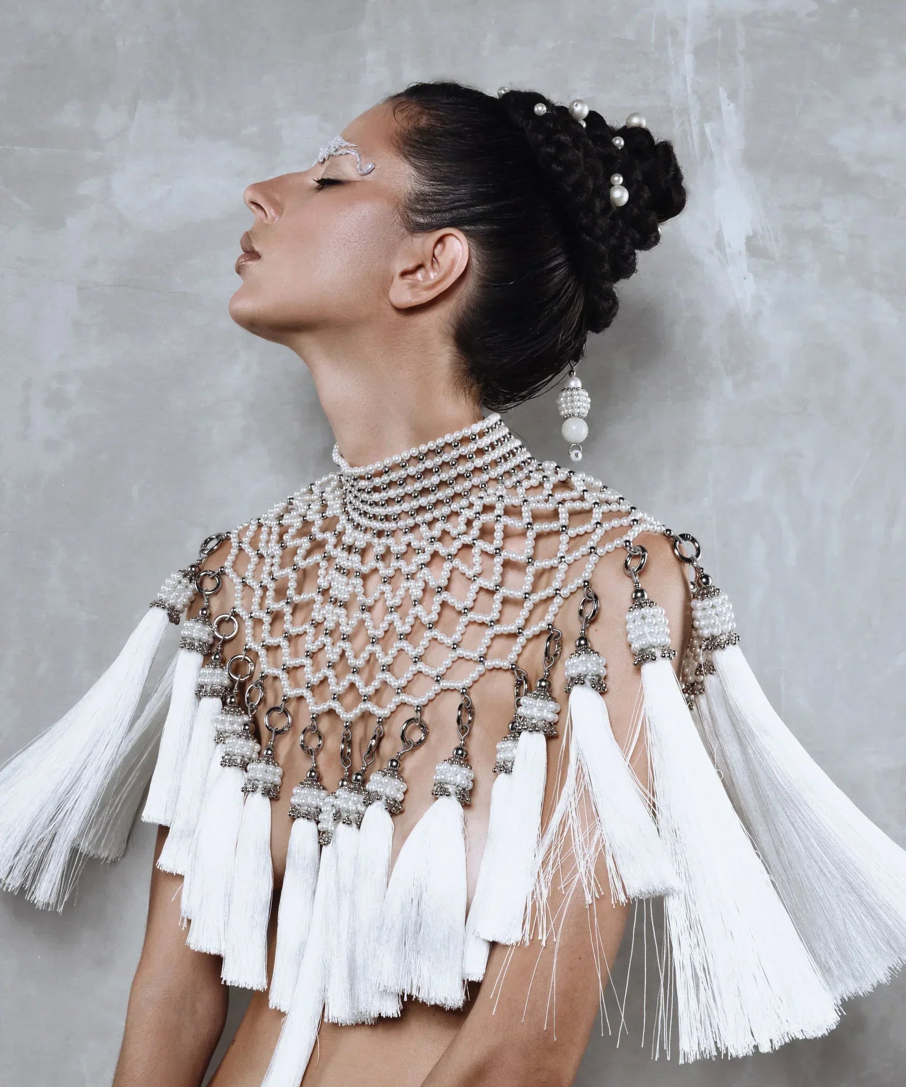 Beaded handcrafted polyester tassel by silver coated metal beads with systethic japanese pearl on Freja Modular Cape on grey background