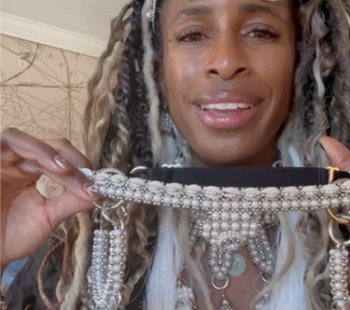 Black woman wearing beaded headband and holding a beaded headpieces looking into camera.