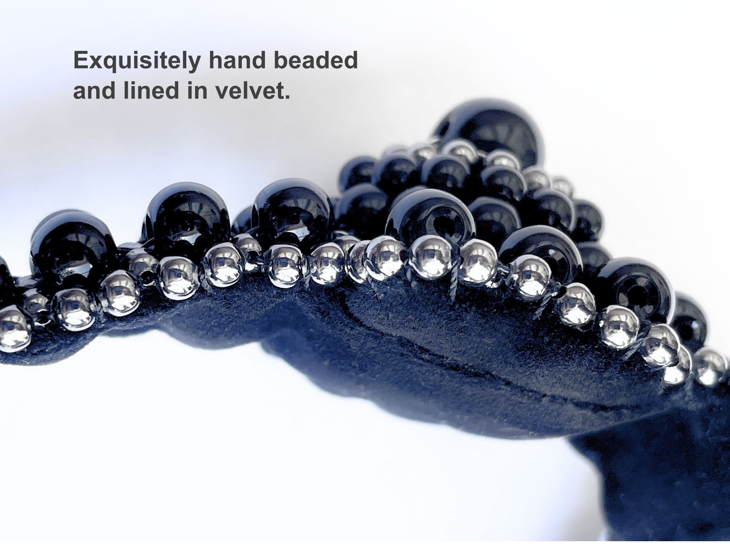 Close-up of a black beaded accessory with text on a white background