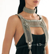 Woman wearing a black dress with a silver beaded harness and choker on a white background