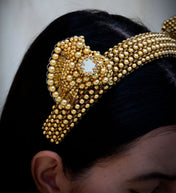 Gold beaded headband worn by a person with a neutral background