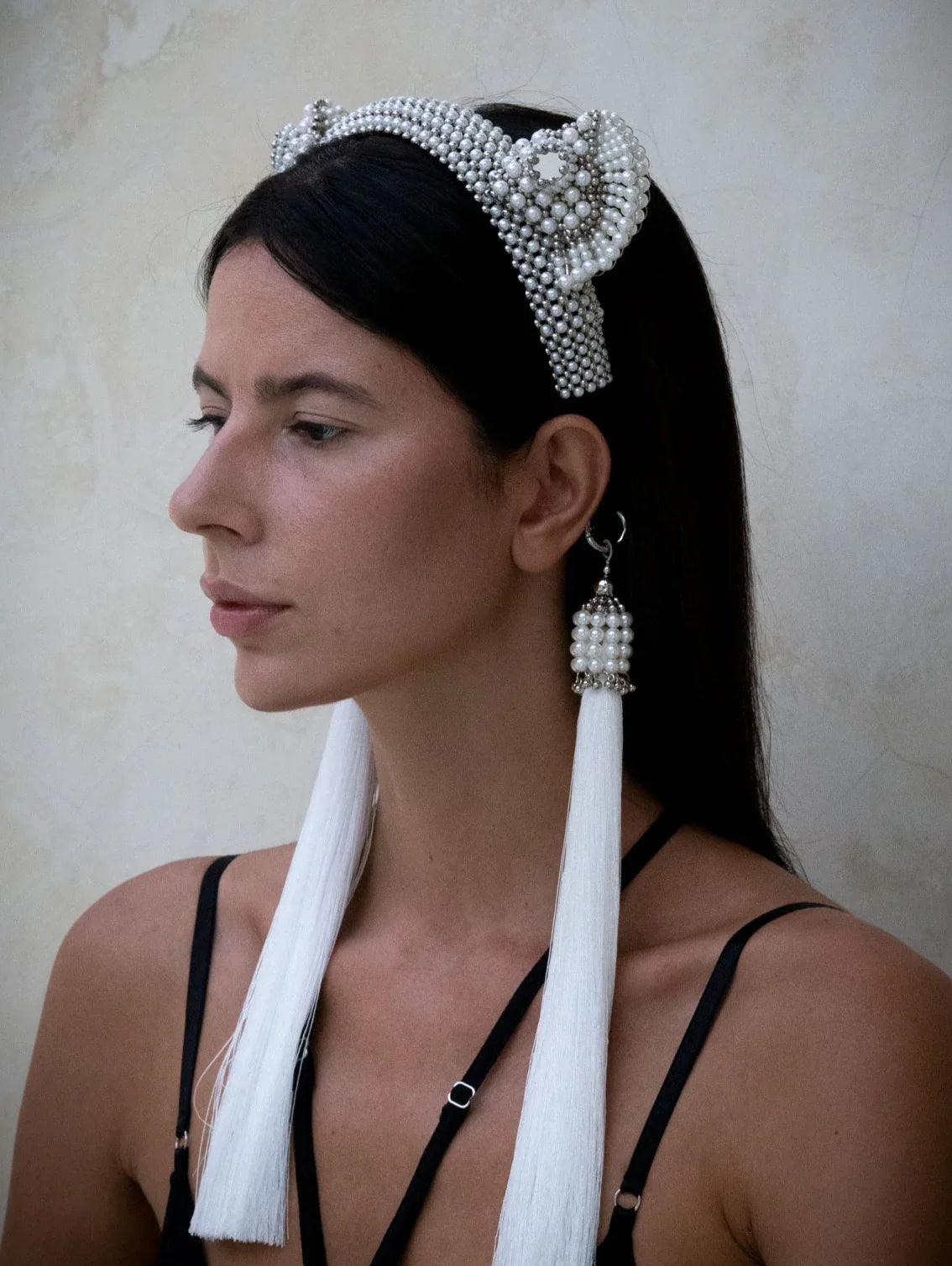 Woman in black outfit wears Jas Headband pearl with 11" tassels pearl by Object &amp; Dawn in neutral backgorund