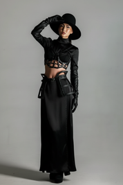 Woman wearing a black outfit with Jas Leather Cage Skirt & Cage Top by Object & Dawn and gloves against a gray background
