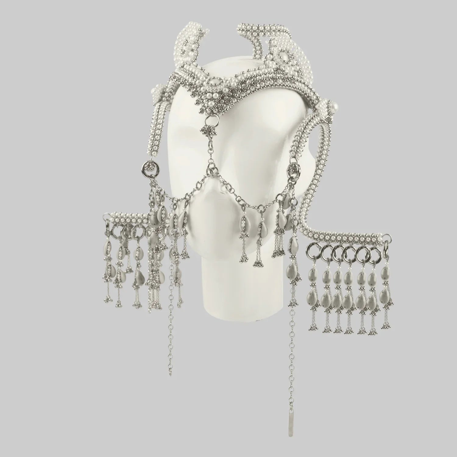 Object and Dawn, modular headpiece system in pearl with removable mask and pearl cowrie tassels in grey background, ghost image front on mannequin diagonal view