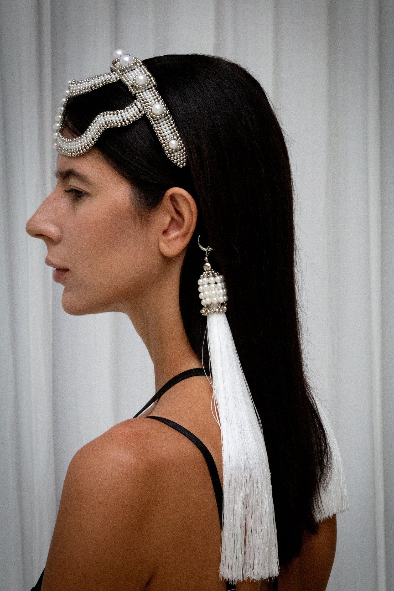 woman wearing handcrafted pearl beaded Khutulun headband in minimal studio setting side view