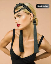 Woman wearing a black headpiece with tassels on a beige background