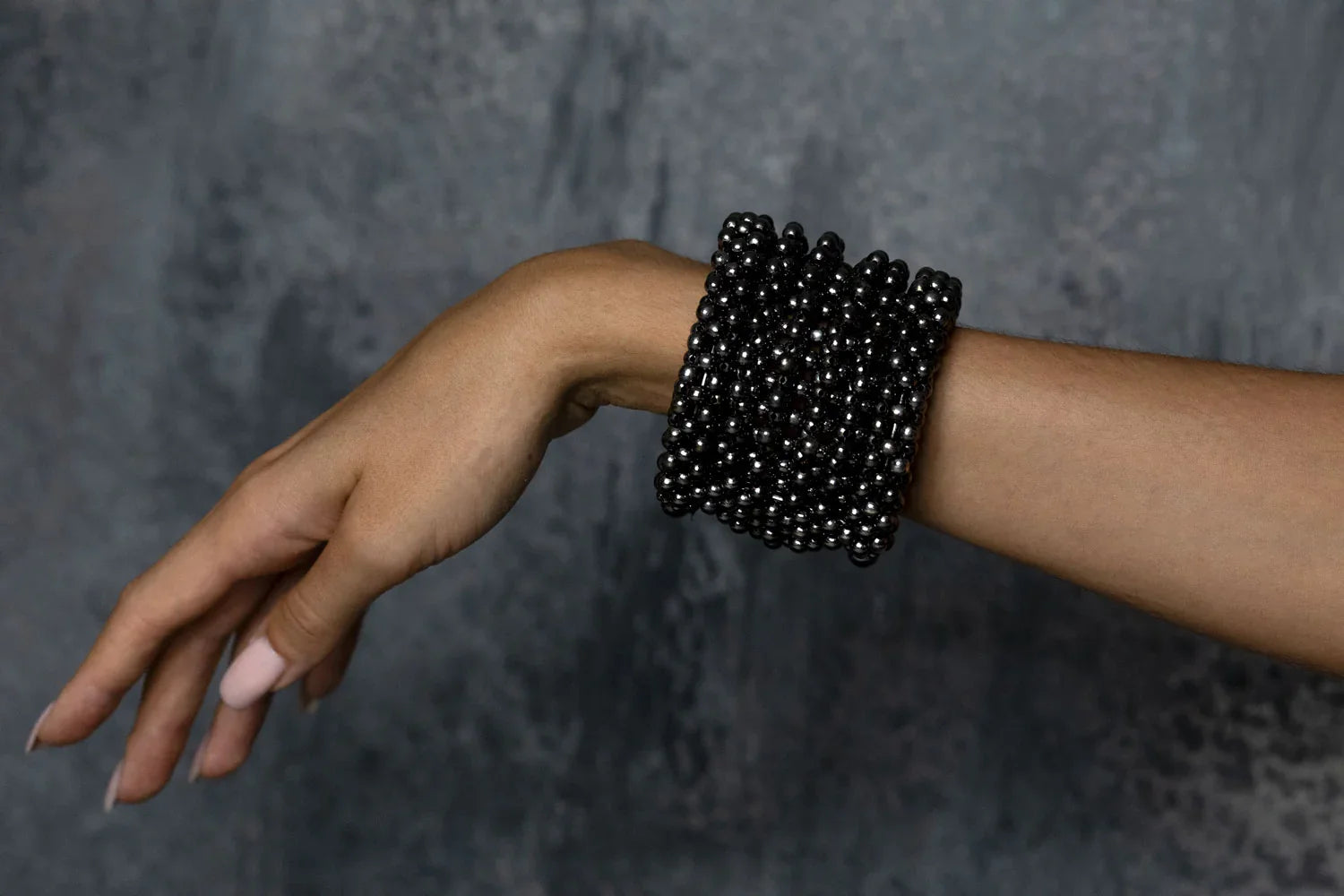 hand of person with handcrafted modular cuff in jet black from hundreds of beads by object and dawn
