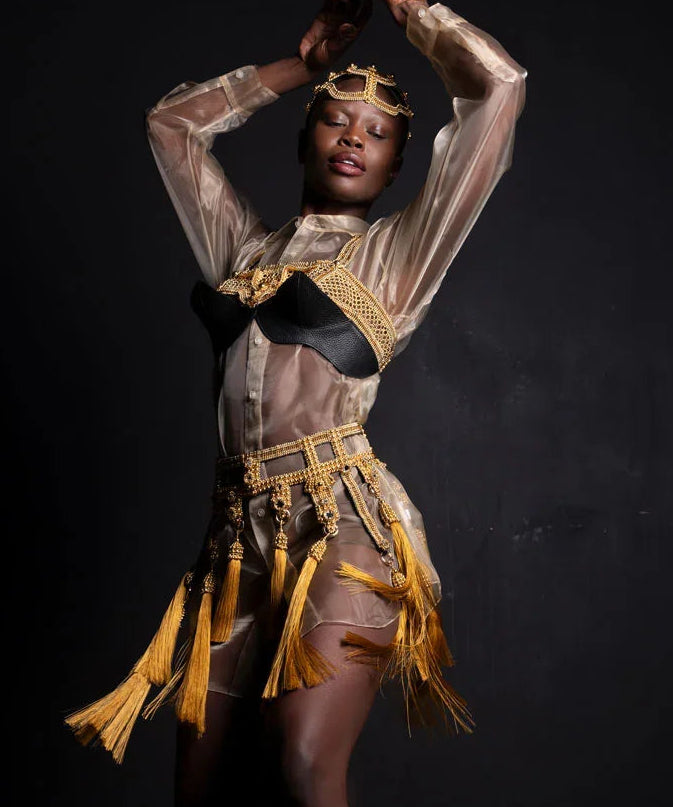 Dancer wearing a gold beaded Amaya belt with gold accents against a dark background