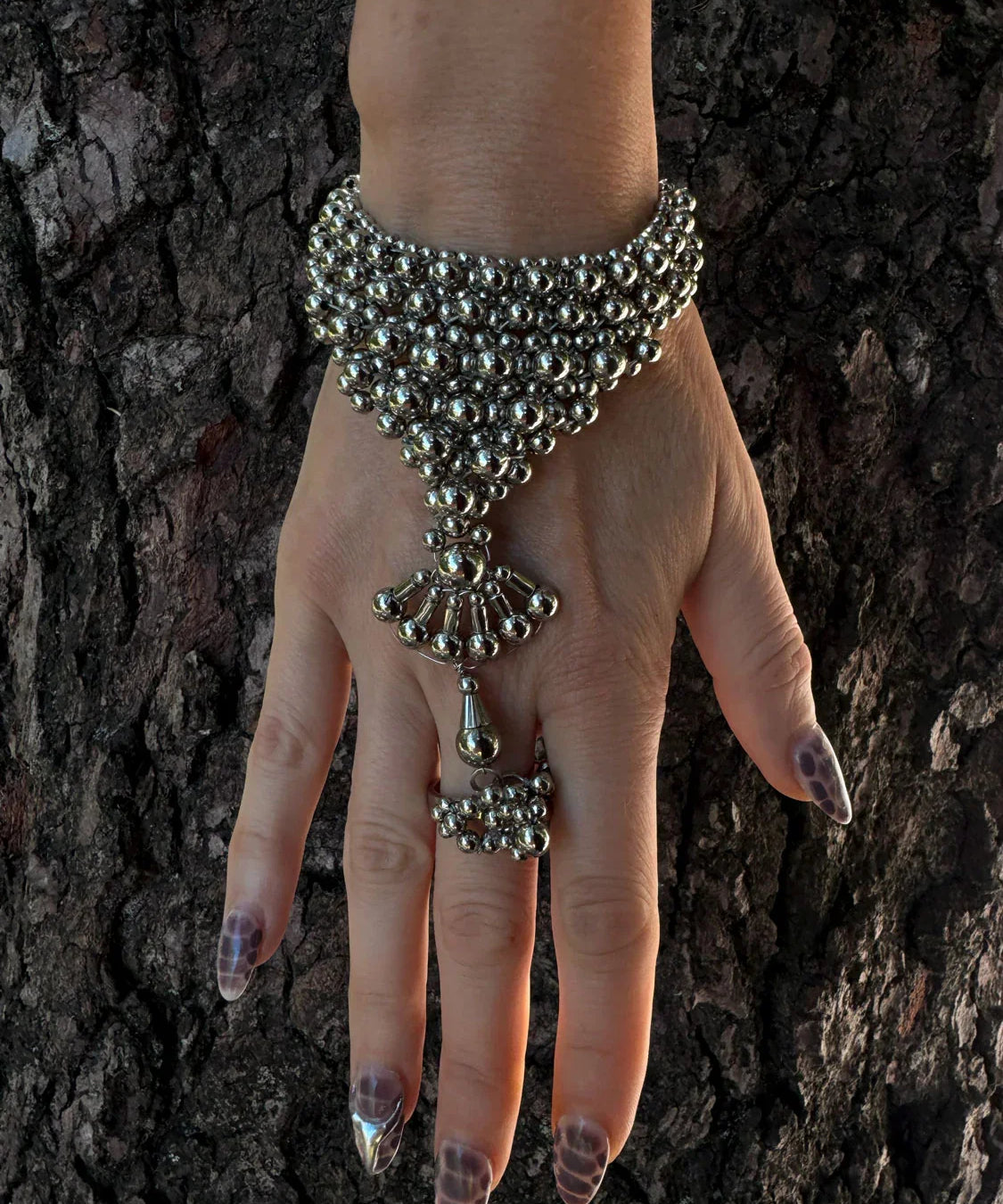 luxury beaded hand jewelry polymer metal beads silver on hand with wood background by object and dawn