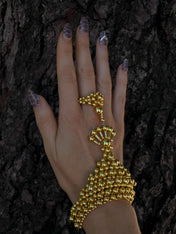 luxury beaded hand jewelry with 22k gold wash on polymer metal beads on hand with wood background by object and dawn