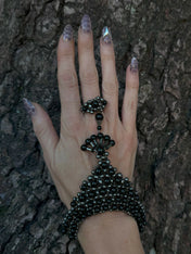 handcrafted beaded hand jewelry polymer metal beads and crystal black on hand with wood background by object and dawn