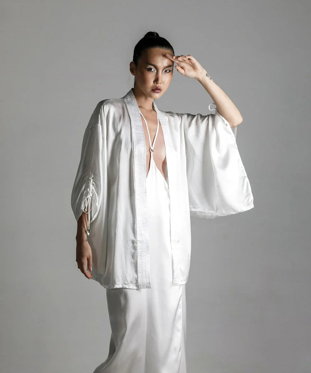 short white silk kimono with white harness skirt worn view up by object and dawn at neutral background