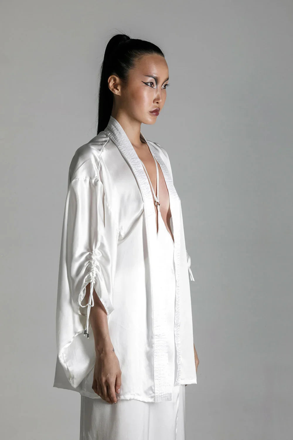 short white silk kimono with white harness skirt worn on woman by object and dawn at neutral background side view