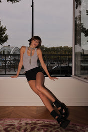 Woman wearing a gray tank top with a decorative t-shaped beaded necklace in an outdoor setting by Object&Dawn.