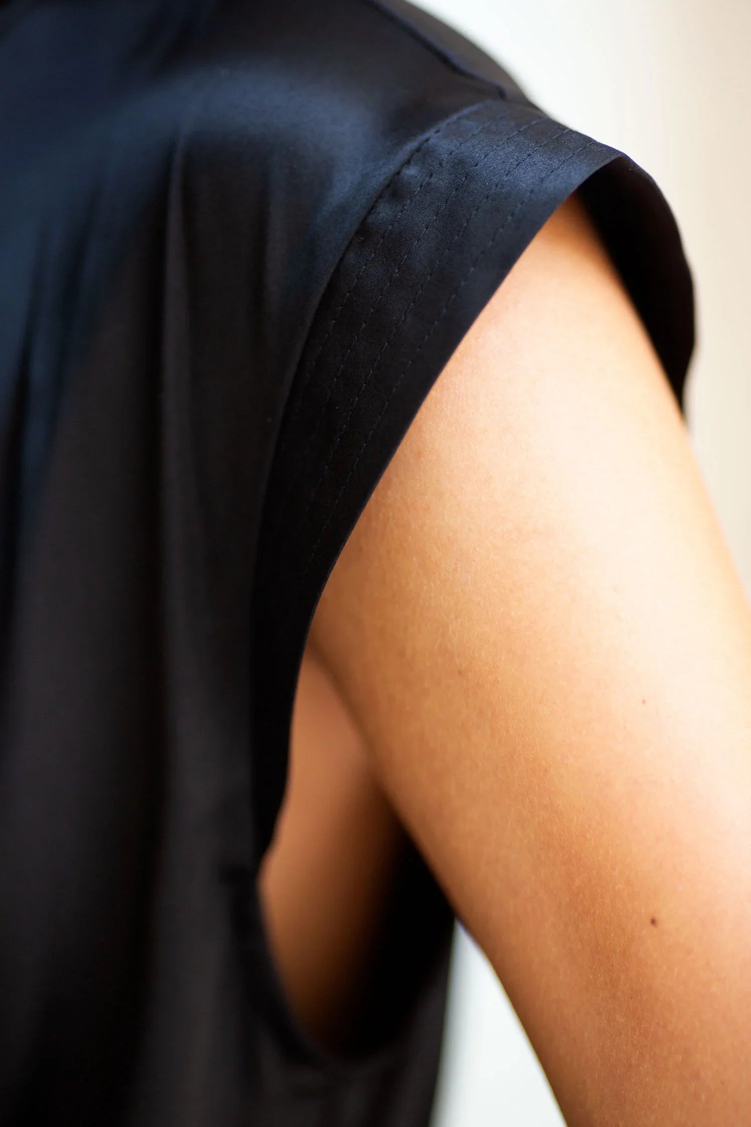 Close-up of woman's shoulder and black silk sleeveless robe. 