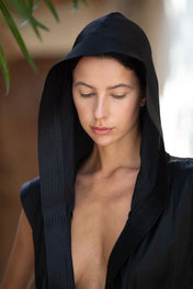 Woman wearing a black hooded silk robe against a blurred background