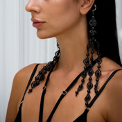 Woman wearing Trinity Medallions Jet Black against a white curtain background