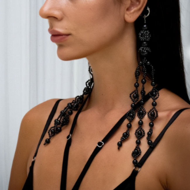 Woman wearing Trinity Medallions Jet Black against a white curtain background