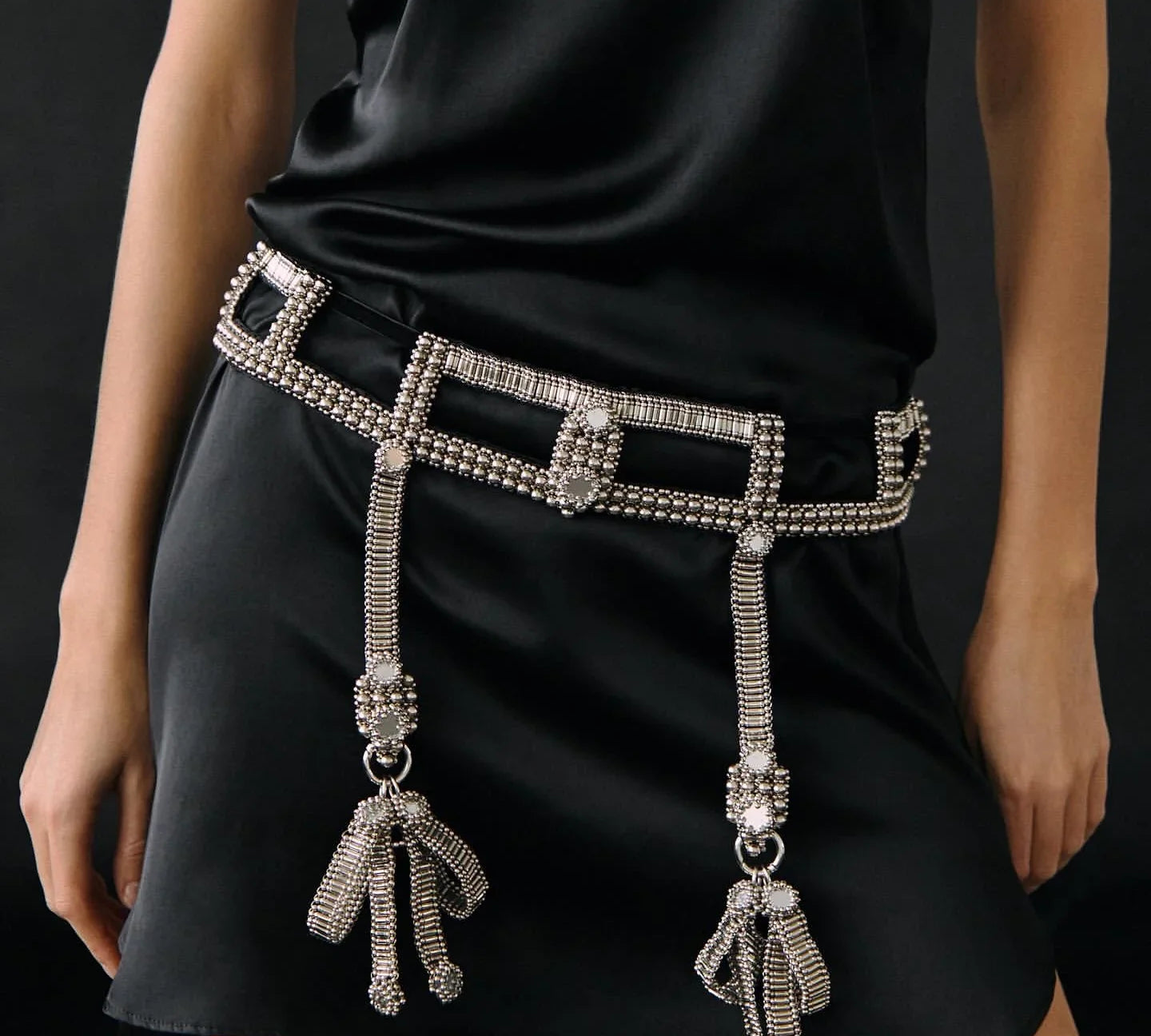 woman standing in black teuta dress wearing teuta belt in silver by Object & Dawn on a black background close up