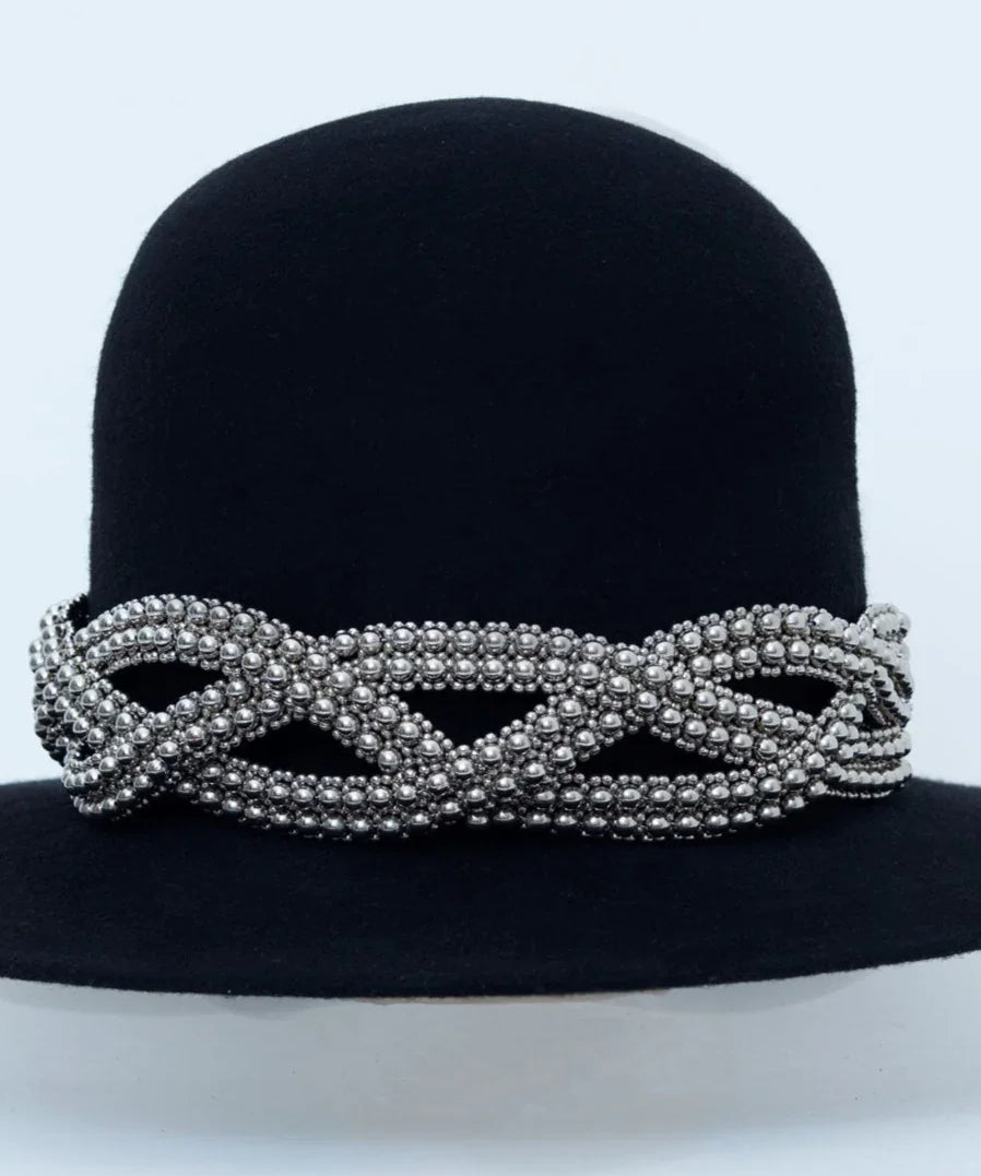 Beaded modular accessory on black hat from polymer metal beads by object and dawn on neutral background