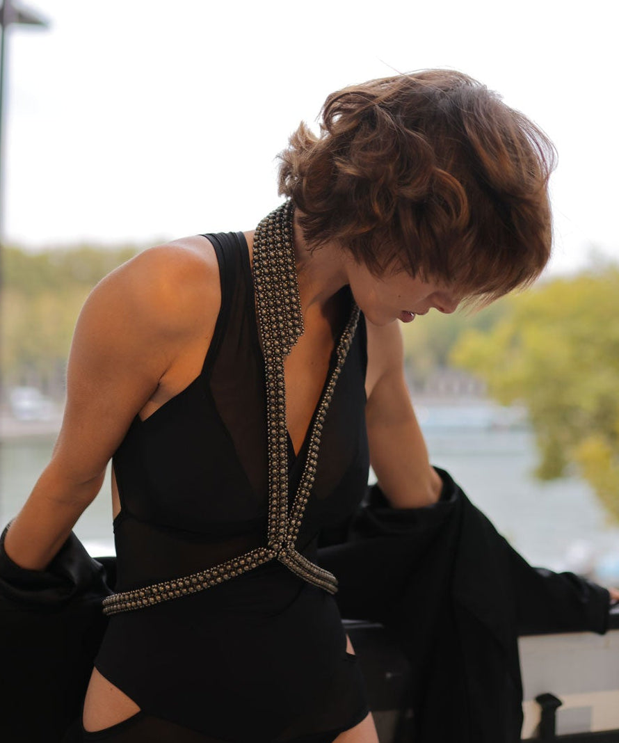 Woman in a black dress with V-Neck Beaded Harness, leaning against a railing with the Eiffel Tower in the background.