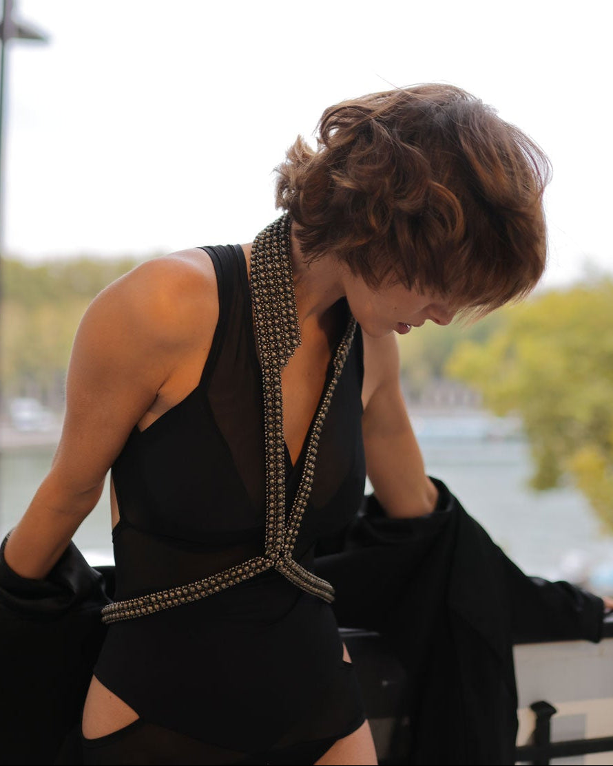 Woman in a black dress with V-Neck Beaded Harness, leaning against a railing with the Eiffel Tower in the background.