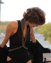 Woman in a black dress with V-Neck Beaded Harness, leaning against a railing with the Eiffel Tower in the background.