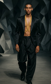 Man wearing a black suit with X-Harness Necklace gold by Object & Dawn on a dark geometric background