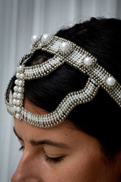 close up woman wearing handcrafted pearl beaded Khutulun headband in minimal studio setting