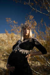 Hera Modular Harness by Object and Dawn is constructed with high quality metal beads that are coated in polymer to preserve shine and ensure the item is hypoallergenic.  Ethically made with secret ancient techniques by our skilled artisans, each piece takes several days to make. The harness is accented with hand cut mirror clusters, locally harvested cowrie shells, custom metal chain tassels and intricate black crystals.  This piece is fully lined by hand in luxurious velvet for your ultimate comfort.